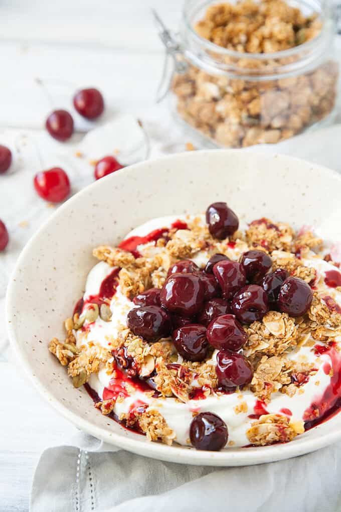 Roasted Cherry Greek Yogurt Bowl - Creamy, luscious Greek yogurt is sprinkled with a delicious, crunchy homemade granola and topped with these lovely Roasted Cherries.