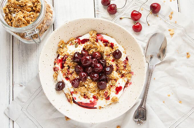 Roasted Cherry Greek Yogurt Bowl - Creamy, luscious Greek yogurt is sprinkled with a delicious, crunchy homemade granola and topped with these lovely Roasted Cherries.