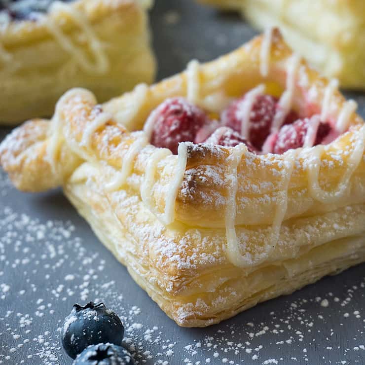 So light and airy, these Berry and Cream Cheese Puff Pastries have buttery, flaky layers with a rich, vanilla-scented cream cheese filling, topped with juicy berries and a drizzle of cream cheese glaze.