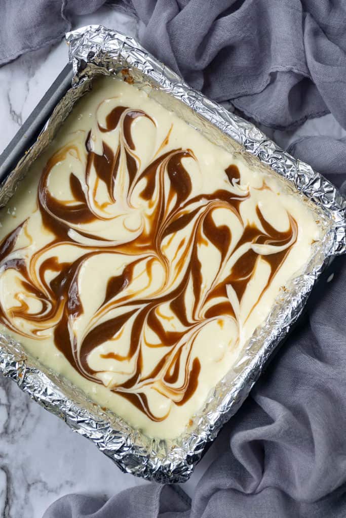 Swirled Caramel Cheesecake Bars - rich, creamy, and velvety smooth cheesecake on top of a sweet, crunchy, shortbread crust, with swirls of rich caramel. All the deliciousness of cheesecake in a quick and easy bar! #cheesecake #cheesecakerecipe #cheesecakebars #bars #caramel #dessert #quick #easy #cheesecakerecipes