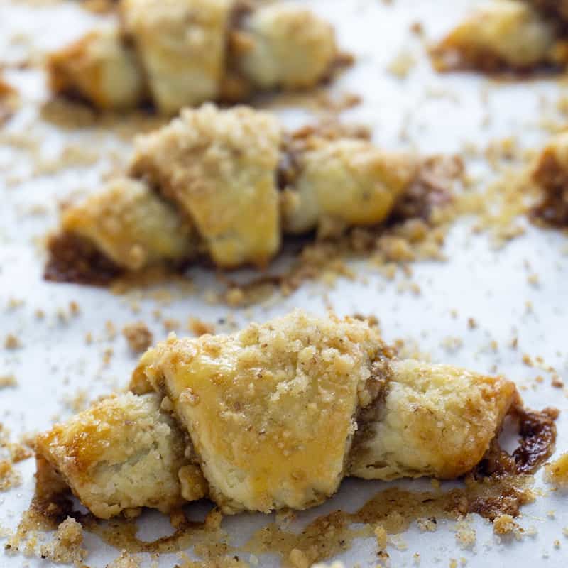 Rugelach, tiny crescent shaped pastries, are afamily favorite. A tender, flaky, cream cheese dough is wrapped around afilling of apricot jam, brown sugar, and walnuts. #rugelach #cookies #cookierecipes #recipes #holidayrecipes #holidaydesserts #holidaycookies