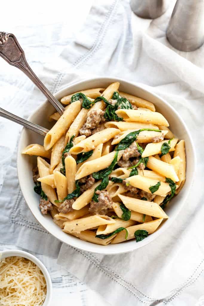 Creamy Italian Sausage Pasta - pasta with sausage and spinach in the creamiest, garlicky parmesan sauce. Pure comfort food on the table in under 30 minutes! #pasta #recipe #easy #quick #under30minutes #easydinner #easyrecipes #sausage #creamy #weeknight #datenight