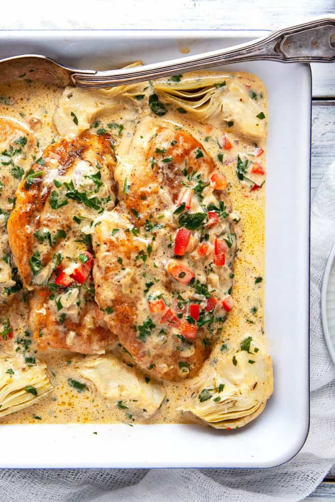 These Creamy Artichoke Chicken Breasts are irresistible! Sautéed chicken breasts are in a lemony, garlicky parmesan cream sauce with artichokes, red peppers, and parsley. On the table in 15 minutes. Quick, easy, delicious. #chicken #chickenbreasts #chickendinner #quick #easy #under30minutes #recipe #lowcarb #keto