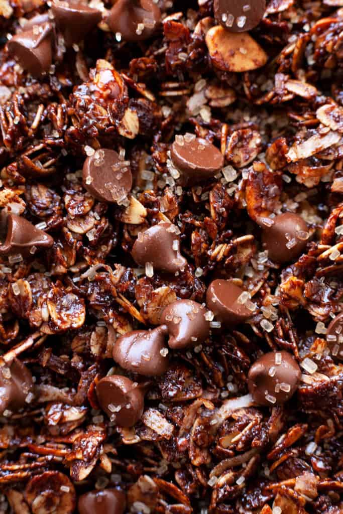 Double Chocolate Granola - crunchy chocolate oat clusters, sliced almonds, flakes of coconut, and best of all – a decadent chocolate coating. Sprinkled with raw sugar for even more crunch. Chocolate for breakfast? Yes, please! #granola #recipe #chocolate #cocoa #breakfast #easy #quick