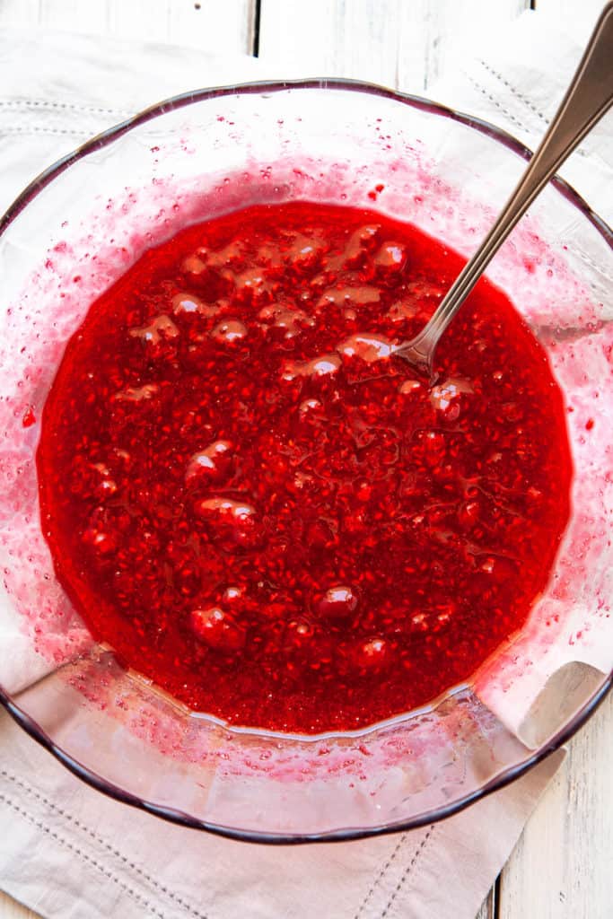 A bright and tangy Raspberry Sauce that needs about 30 seconds of hands on time. It practically makes itself. Once you taste it, you’ll start dreaming of all the things you can drizzle it over. #raspberry #sauce #easy #quick #desserts #recipe #homemade #foricecream #forwaffles #microwave #simple