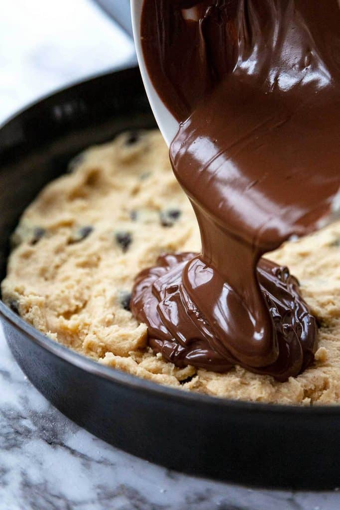 Nutella-Stuffed, Deep Dish, Chocolate Chip Skillet Cookie - A crispy, chewy, buttery chocolate chip cookie on the outside and an irresistible, ooey-gooey Nutella-stuffed center, baked in a cast iron pan. Serve warm from the oven with vanilla ice cream for the ultimate dessert! #skilletcookie #castiron #easy #chocolatechip #withpremadedough #videos #recipe #gooey #stuffed #nutella #giant #best #sundae #homemade #deepdish #12inch #10inch #individual