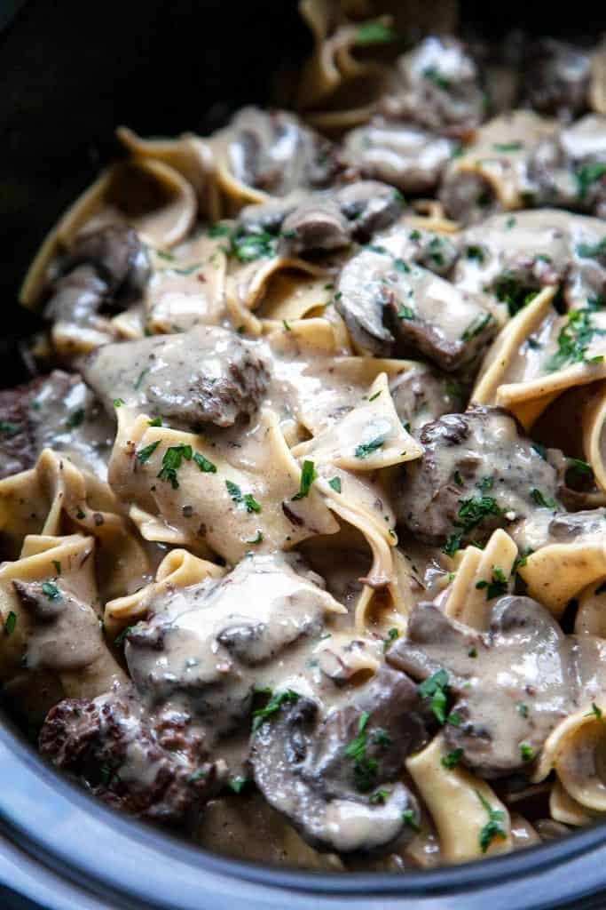 The most incredible Slow Cooker Beef Stroganoff you will ever have! Melt-in-your-mouth tender chunks of beef slowly simmered in a creamy mushroom sauce. As easy as it is delicious! A cozy, comforting meal the whole family will love. #beef #beefstroganoff #stroganoff #easy #crockpot #slowcooker #recipe #best #withstewmeat #traditional #creamy #videos #fromscratch #dinner #easydinner