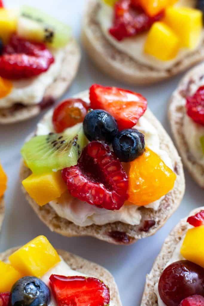 Mini Fruit Pizzas with fresh juicy fruit, velvety smooth cream cheese, and a soft, chewy crust. A delicious and healthy snack your whole family will love! Quick and easy to make with wholesome ingredients you can feel good about serving.