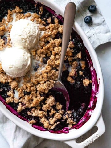 dish of blueberry crisp topped with ice cream