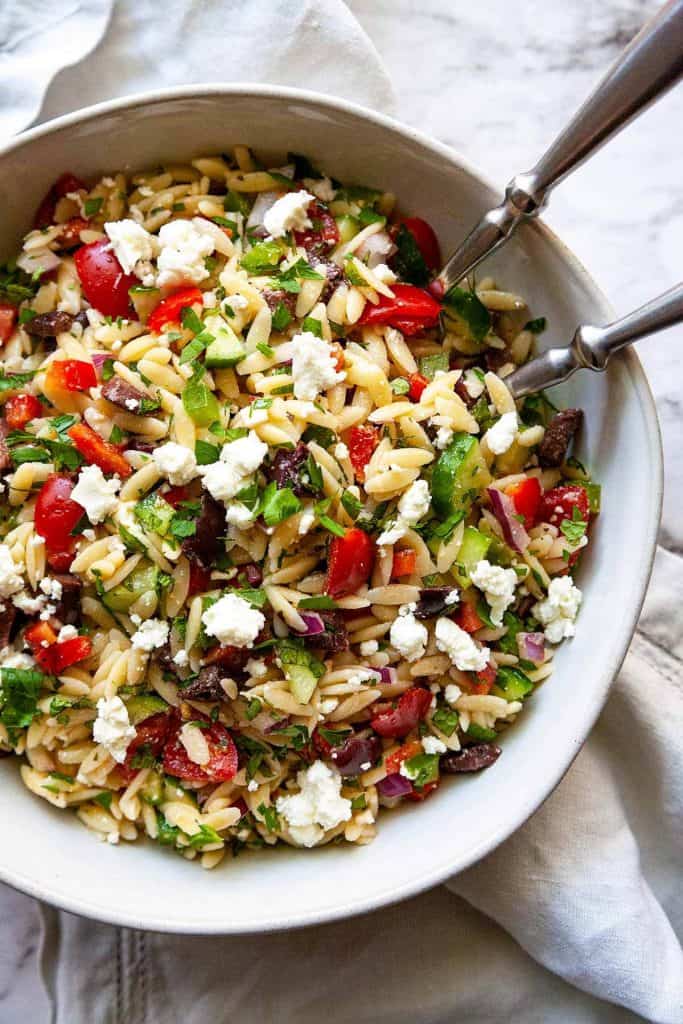 Quick and easy to make Greek Orzo Salad is loaded with fresh crunchy veggies and all of your favorite Mediterranean flavors. This healthy pasta salad recipe is perfect for picnics, potlucks, or barbeques or as an easy, flavorful side dish for dinner.