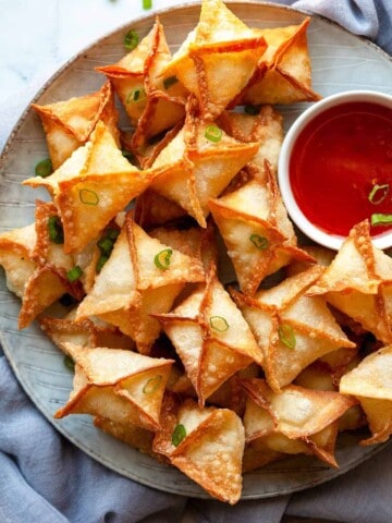 a plate of fried rangoon and a dish of sweet chili sauce.