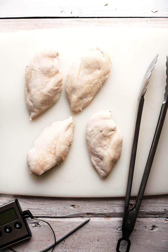 Poached chicken breasts on cutting board