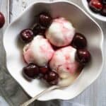 a bowl of vanilla ice cream topped with roasted cherry sauce