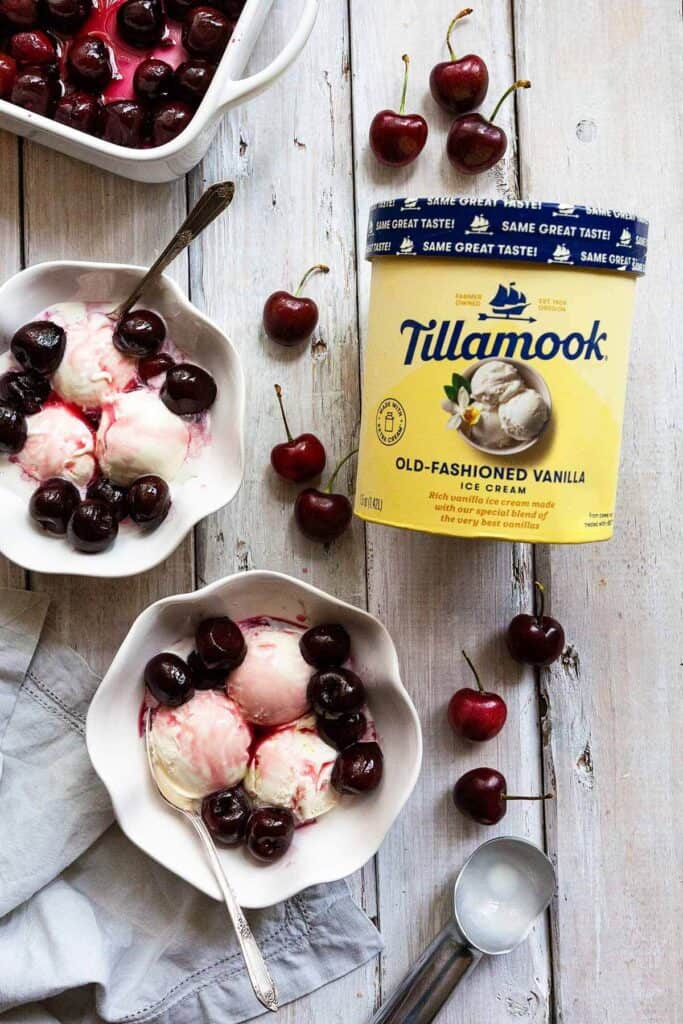 Tillamook ice cream in container, a dish of roasted cherry sauce, and two bowls of ice cream with cherry sauce