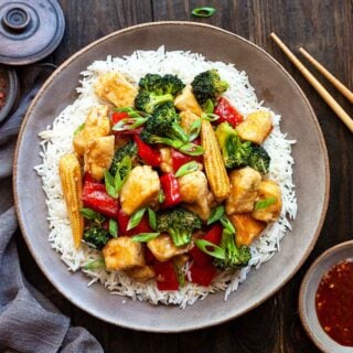 a dish of Hunan chicken with rice and chopsticks