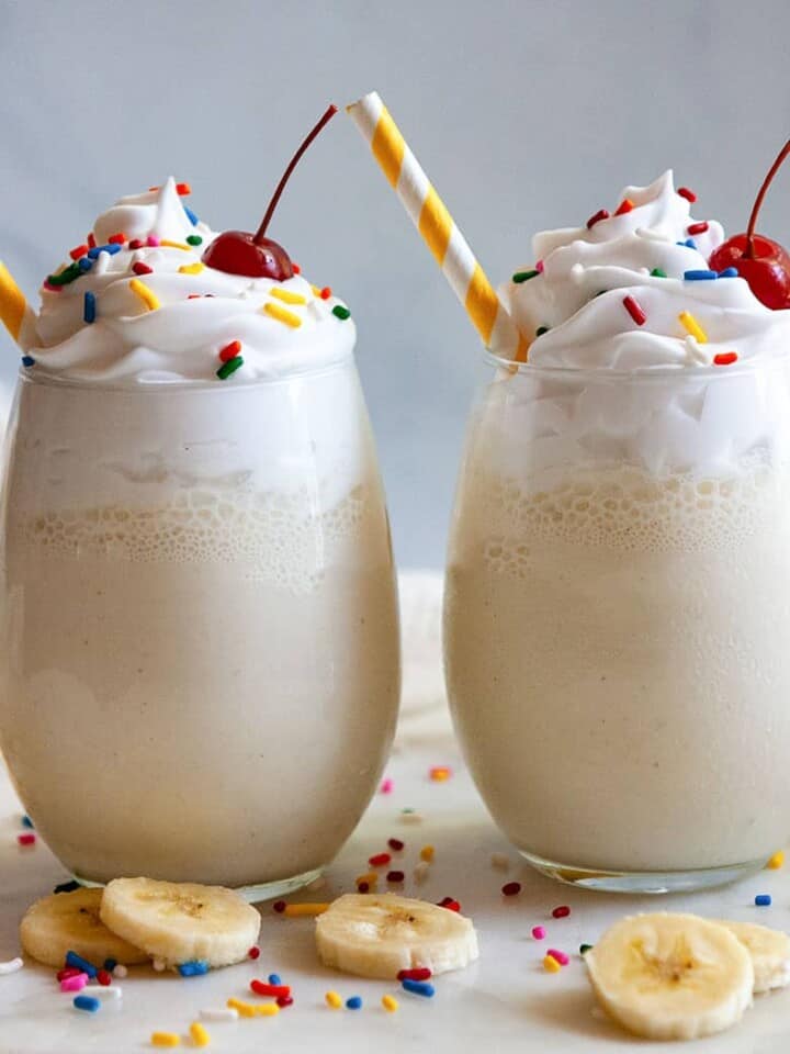 two banana milkshakes topped with sprinkles and cherries