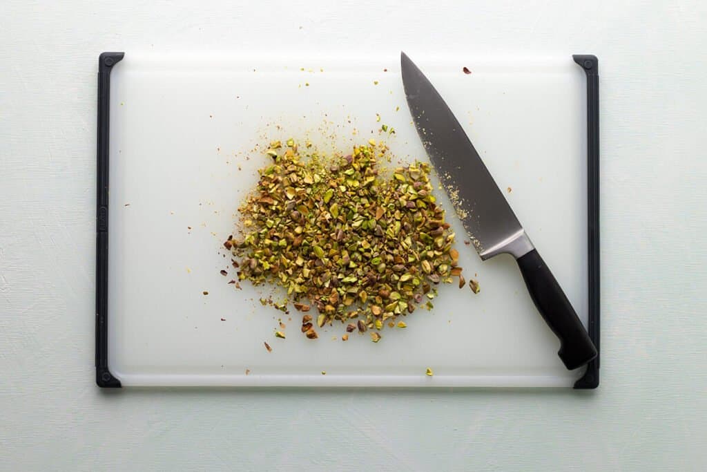 chopped pistachios on a cutting board with knife