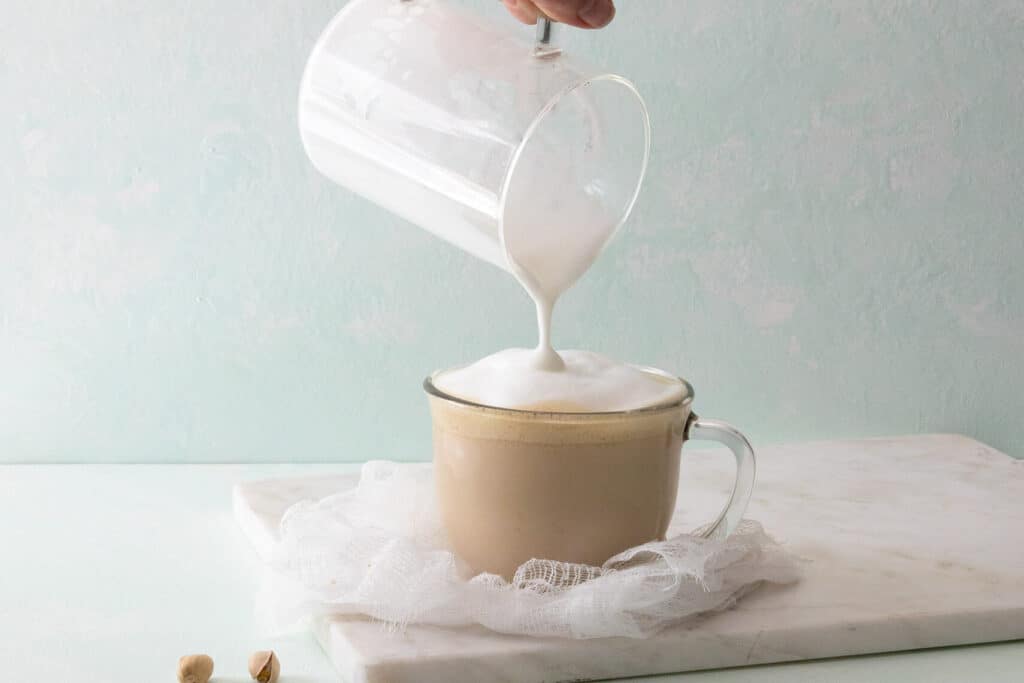 pouring foamed milk on latte