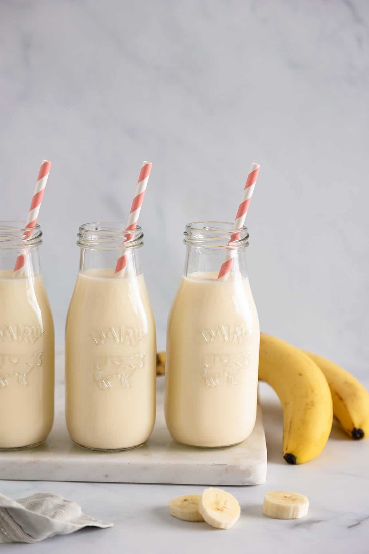 three bottles of banana milk with straws and two bananas