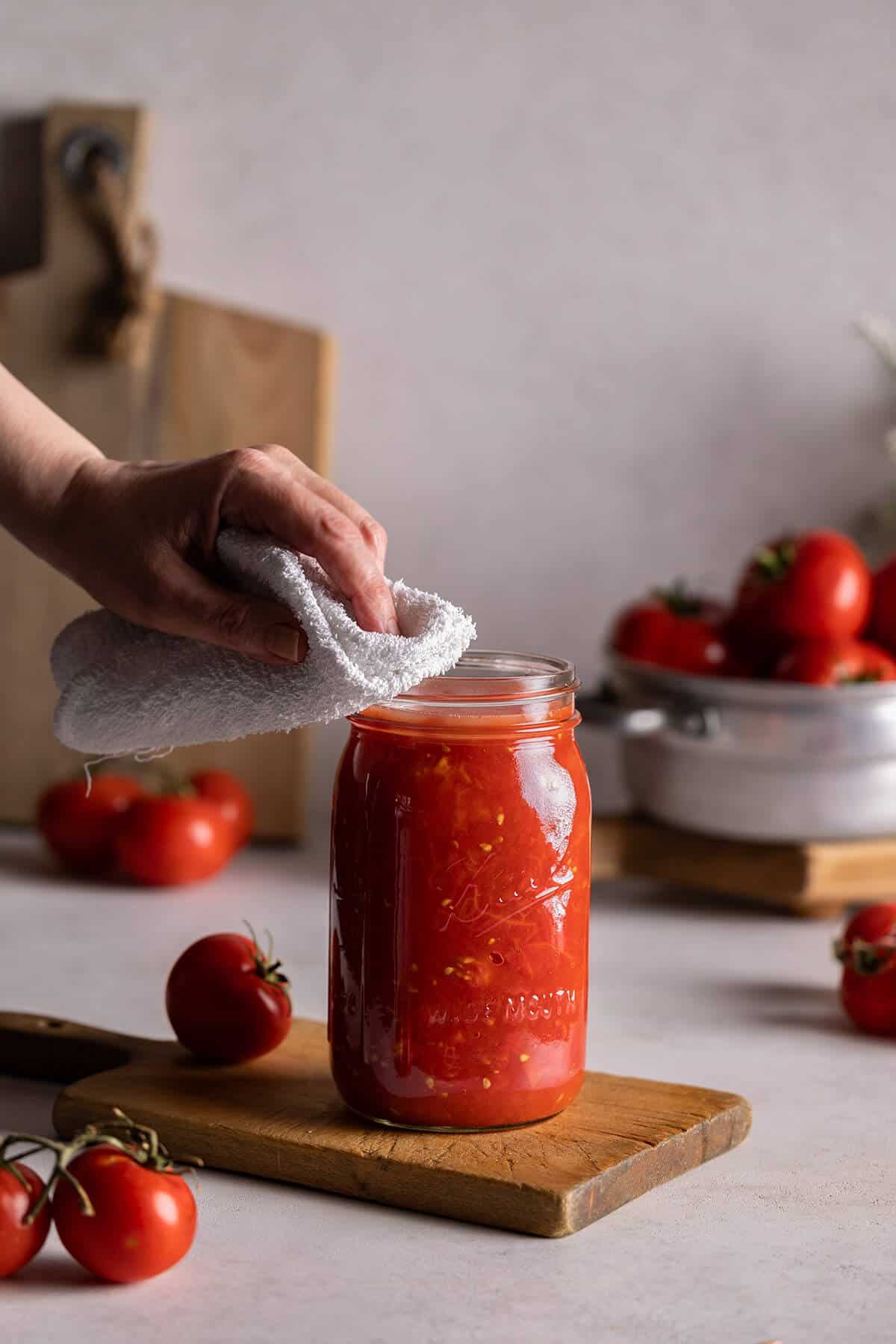 wiping the rim on a jar of tomatoes